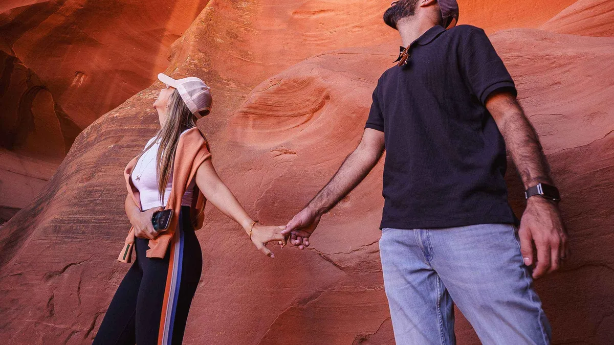 Couple photographed handheld between glowing sandstone walls on a private Antelope Canyon photoshoot session that follows current photography rules